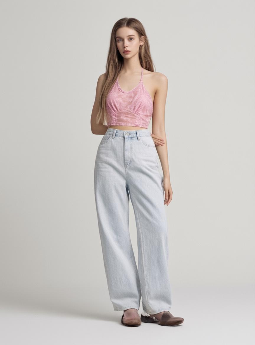 A Woman Is Posing In A Casual Outfit Featuring A Pink Top And Light-Wash Jeans Against A Plain Studio Backdrop