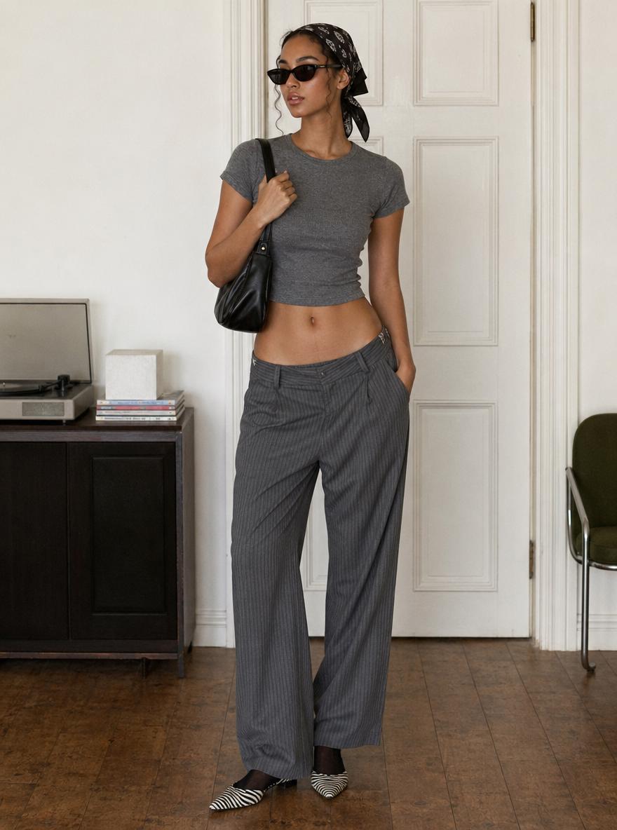 A Woman Stands Confidently In A Stylish Outfit In A Minimalistic Indoor Setting Featuring A Vintage Record Player And Elegant Furniture