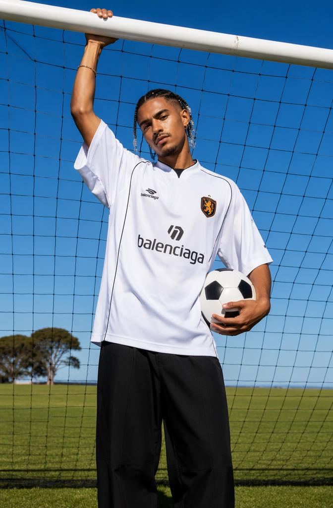 The striking contrast between the clean white oversized designer soccer jersey and the da...