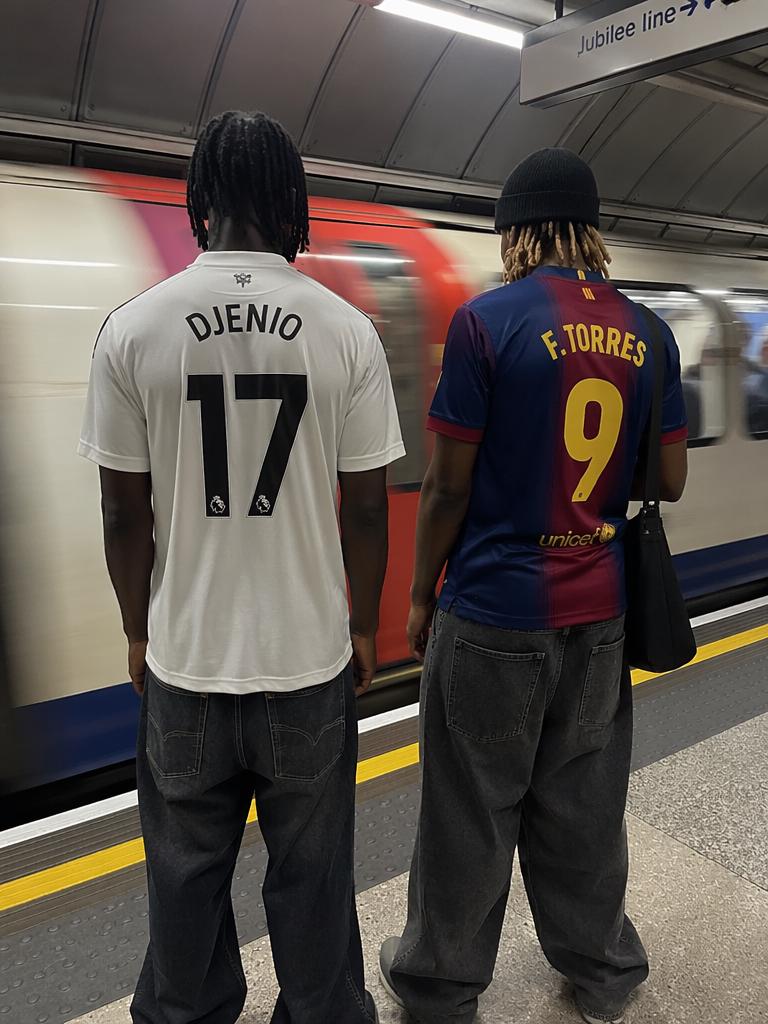 The contrast between two individuals in iconic football jerseys seen from behind, positio...