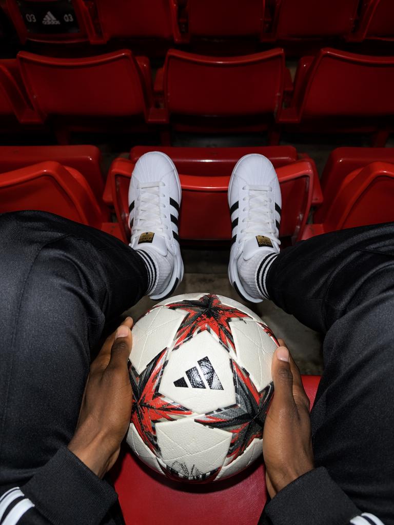 The stark color contrast between clean white Adidas sneakers and the vibrant, uniform red...