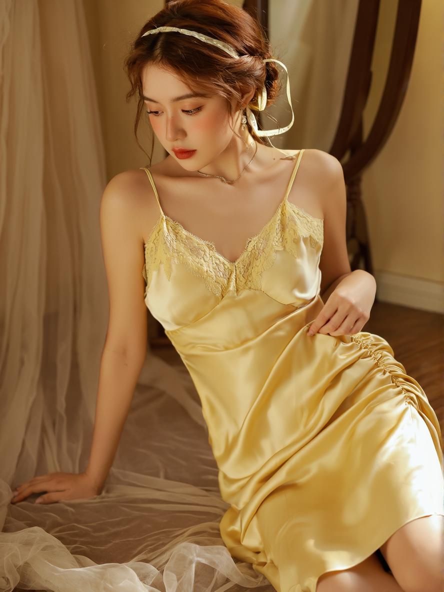 A Woman In An Elegant Yellow Satin Dress Sits In A Softly Lit Room With Sheer Curtains And Wooden Accents